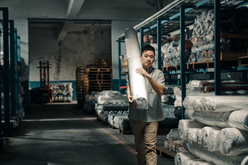 Worker carries roll of fabric made from recycled plastic